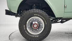 Side view of front tire and suspension underneath mint green Classic Ford Bronco