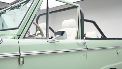 Open driver side door showing black side mirror and white seats inside Classic Ford Bronco