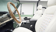Interior view of Classic Ford Bronco showing wooden steering wheel, dashboard, and pedals