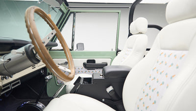 Interior view of Classic Ford Bronco showing wooden steering wheel, dashboard, and pedals