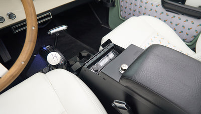 Classic Ford Bronco interior showing wooden steering wheel, white seats, center console and radio