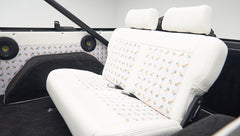 Classic Ford Bronco back seat with white upholstery featuring ice cream cone pattern and black speakers