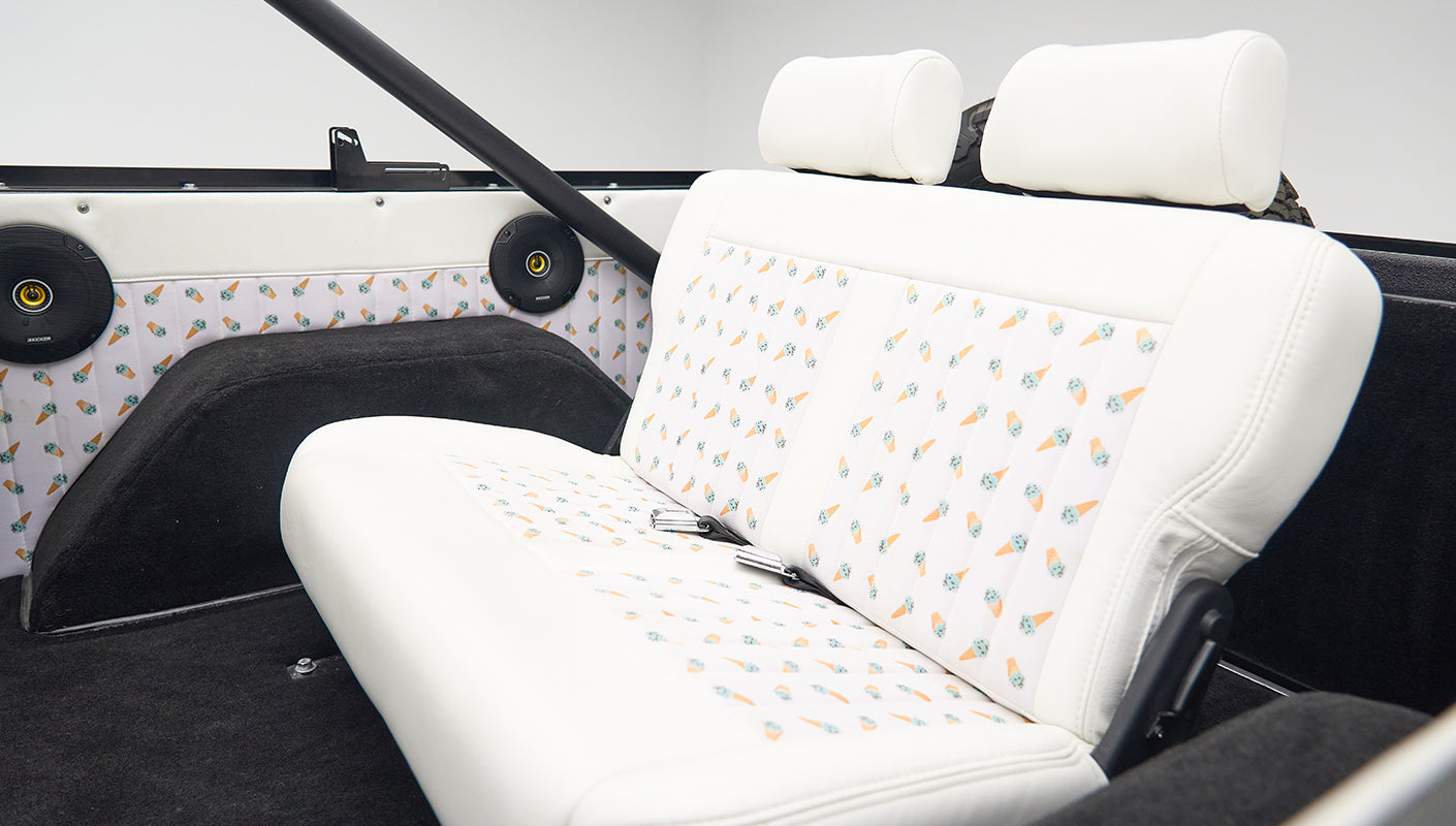 Classic Ford Bronco back seat with white upholstery featuring ice cream cone pattern and black speakers