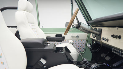 Interior from passenger side showing dashboard, black armrest, and white seats with pineapple pattern