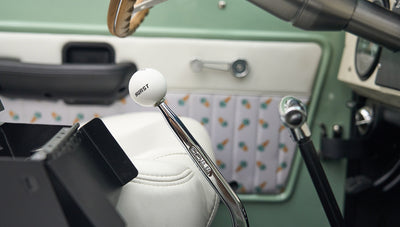 Close-up of Hurst gear shifter and white leather seats with ice cream cone pattern inside a Classic Ford Bronco