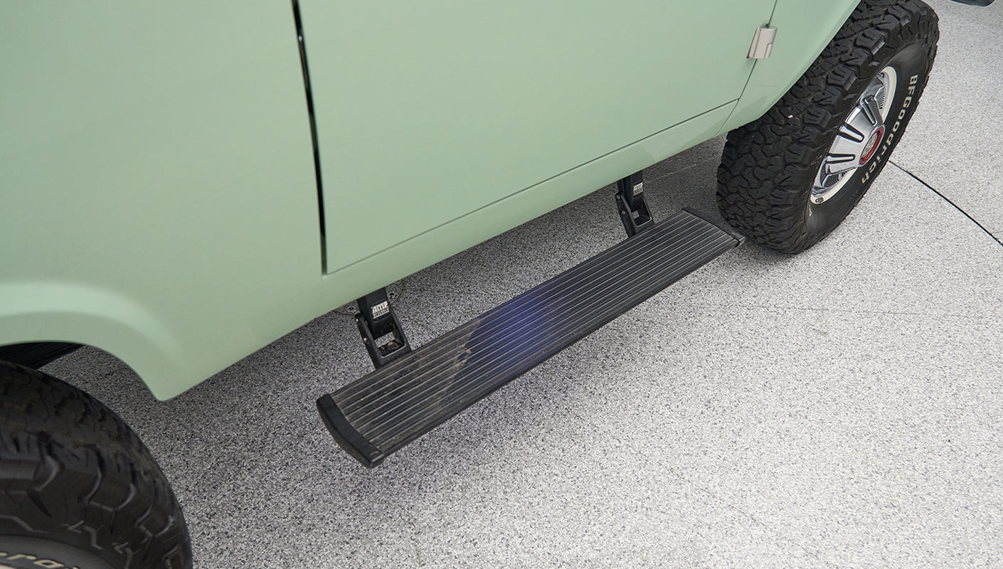 Side step and rear wheel of a light green Classic Ford Bronco