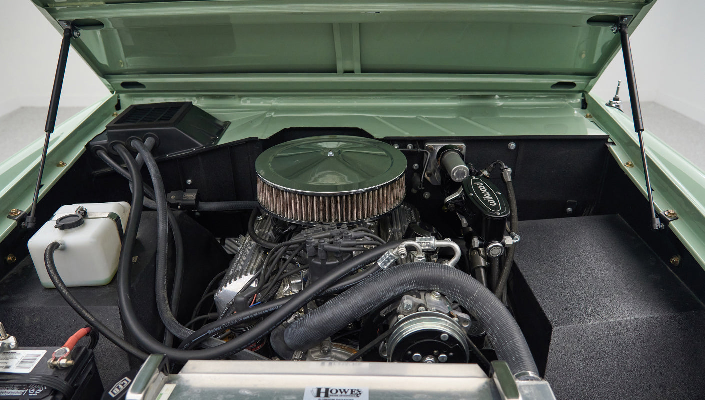 Wide view of engine bay under hood of a Classic Ford Bronco, showing clean engine and radiator components
