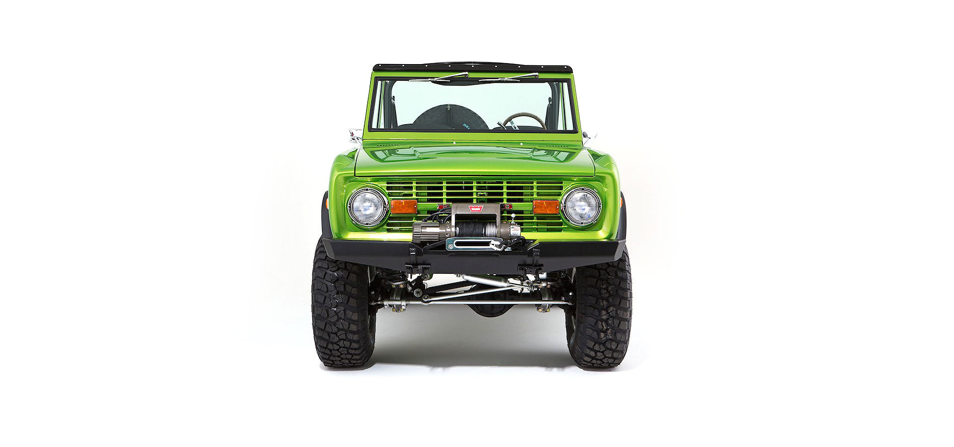 Front view of bright green Classic Ford Bronco with winch and rugged tires on white background