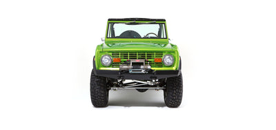 Front view of bright green Classic Ford Bronco with winch and rugged tires on white background