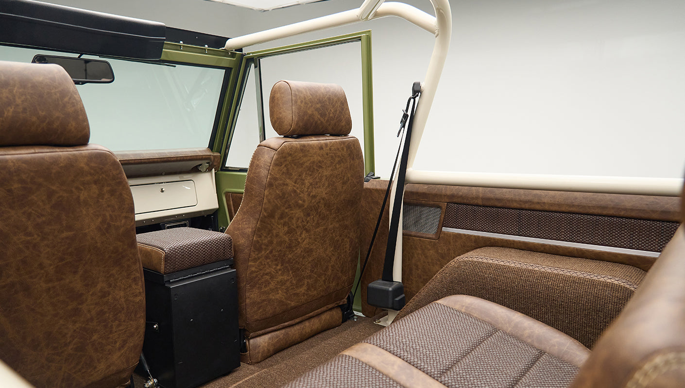 Rear view of Classic Ford Bronco interior showing brown leather seats and beige roll cage