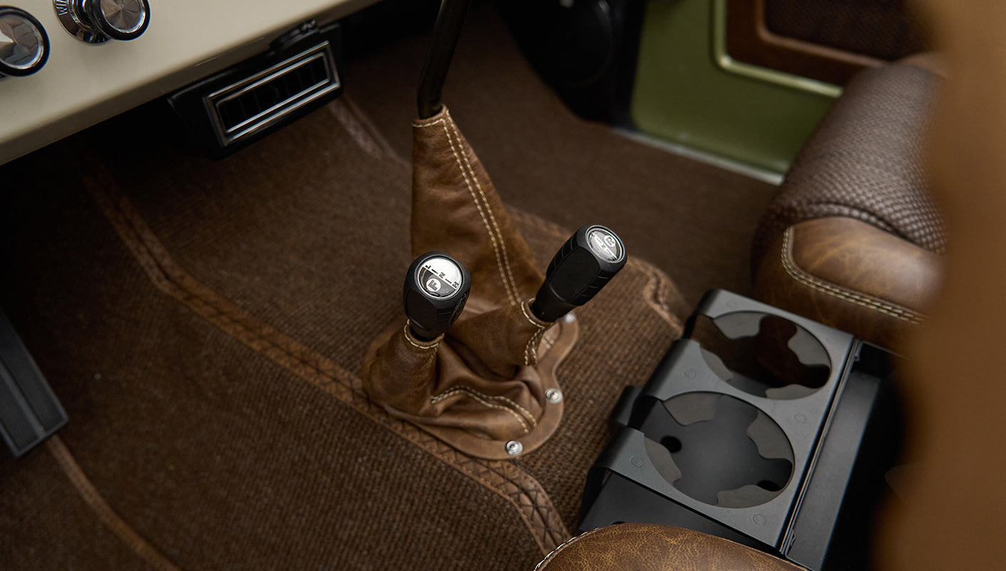 Two leather shift handles and cup holder console between brown seats in Classic Ford Bronco interior