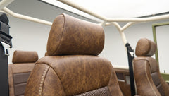 Close-up of brown leather headrest and seats with roll cage in Classic Ford Bronco interior