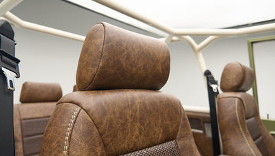 Close-up of brown leather headrest and seats with roll cage in Classic Ford Bronco interior