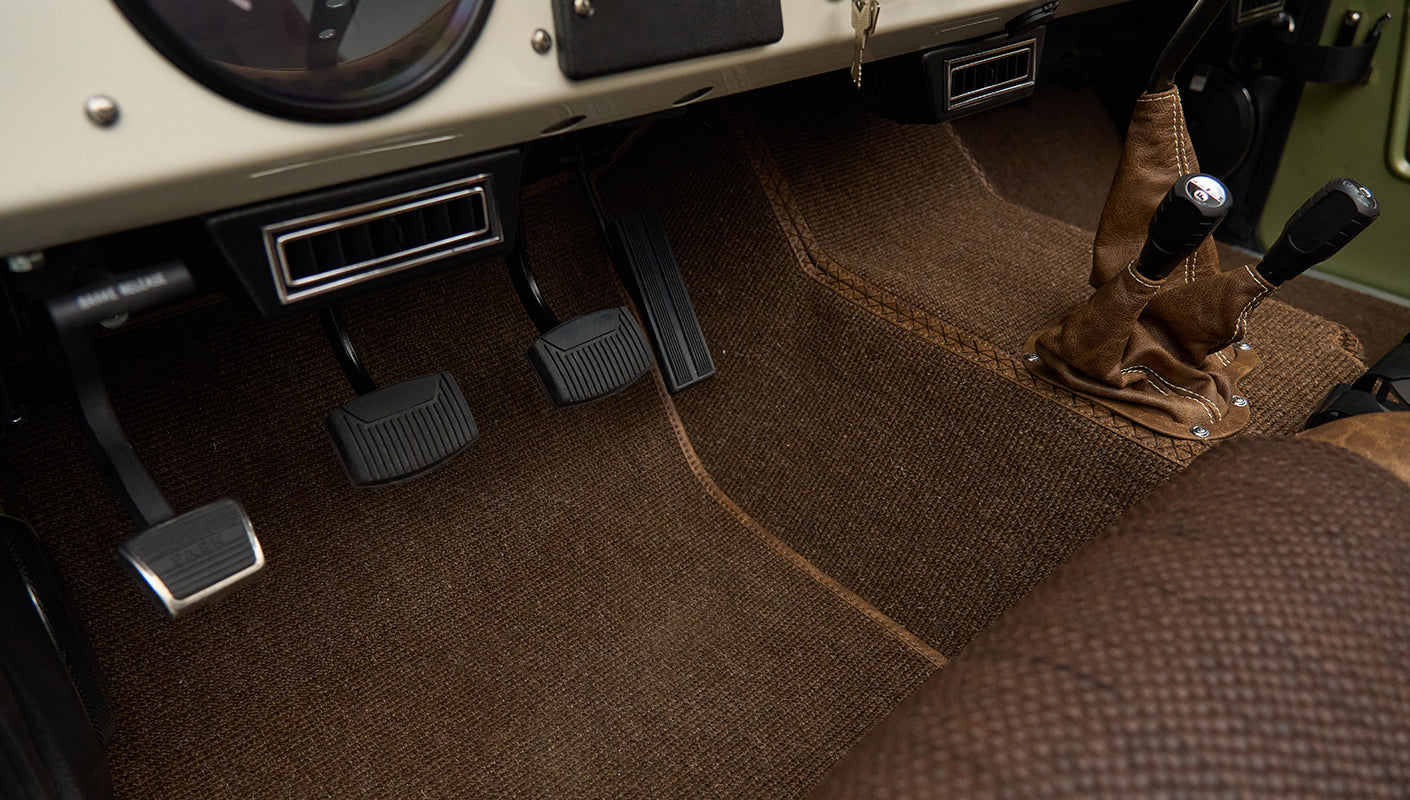 Brown carpeted floor with three pedals and two leather shift boots in Classic Ford Bronco interior