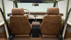 Front seats of Classic Ford Bronco from rear, showing brown leather upholstery and dashboard