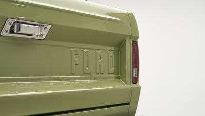Rear tailgate of Classic Ford Bronco in lime gold color with embossed FORD lettering and taillight