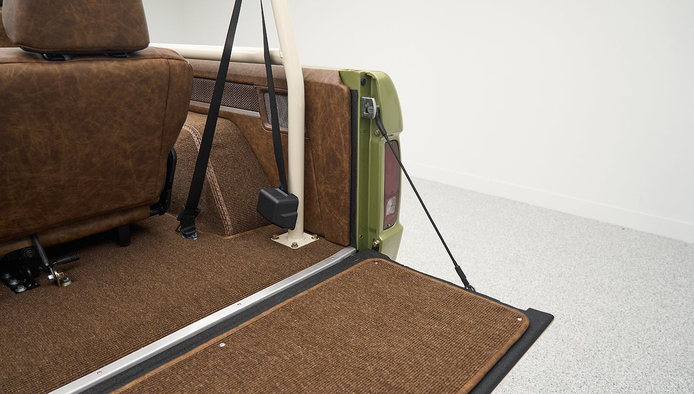 Rear cargo area of Classic Ford Bronco with brown upholstery and beige roll cage