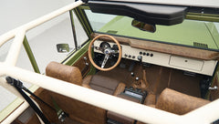 Overhead view into Classic Ford Bronco showing steering wheel, gear shifts, and brown seats