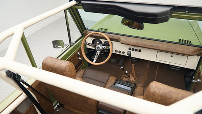 Overhead view into Classic Ford Bronco showing steering wheel, gear shifts, and brown seats