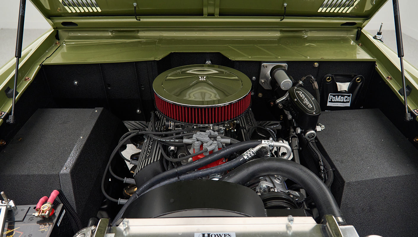 Engine compartment of Classic Ford Bronco in lime gold showing air filter and wiring