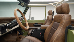 Angle view of front seats inside Classic Ford Bronco Lime Gold showing brown upholstery and steering wheel