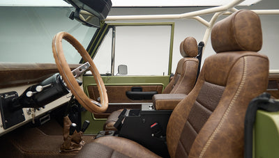 Angle view of front seats inside Classic Ford Bronco Lime Gold showing brown upholstery and steering wheel