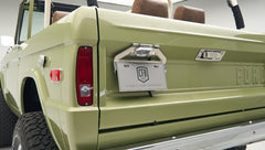 Close-up of rear of lime green Classic Ford Bronco showing tailgate, taillights, and license plate