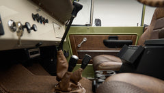 Driver's side interior of Classic Ford Bronco showing seats, gear levers, and door panel