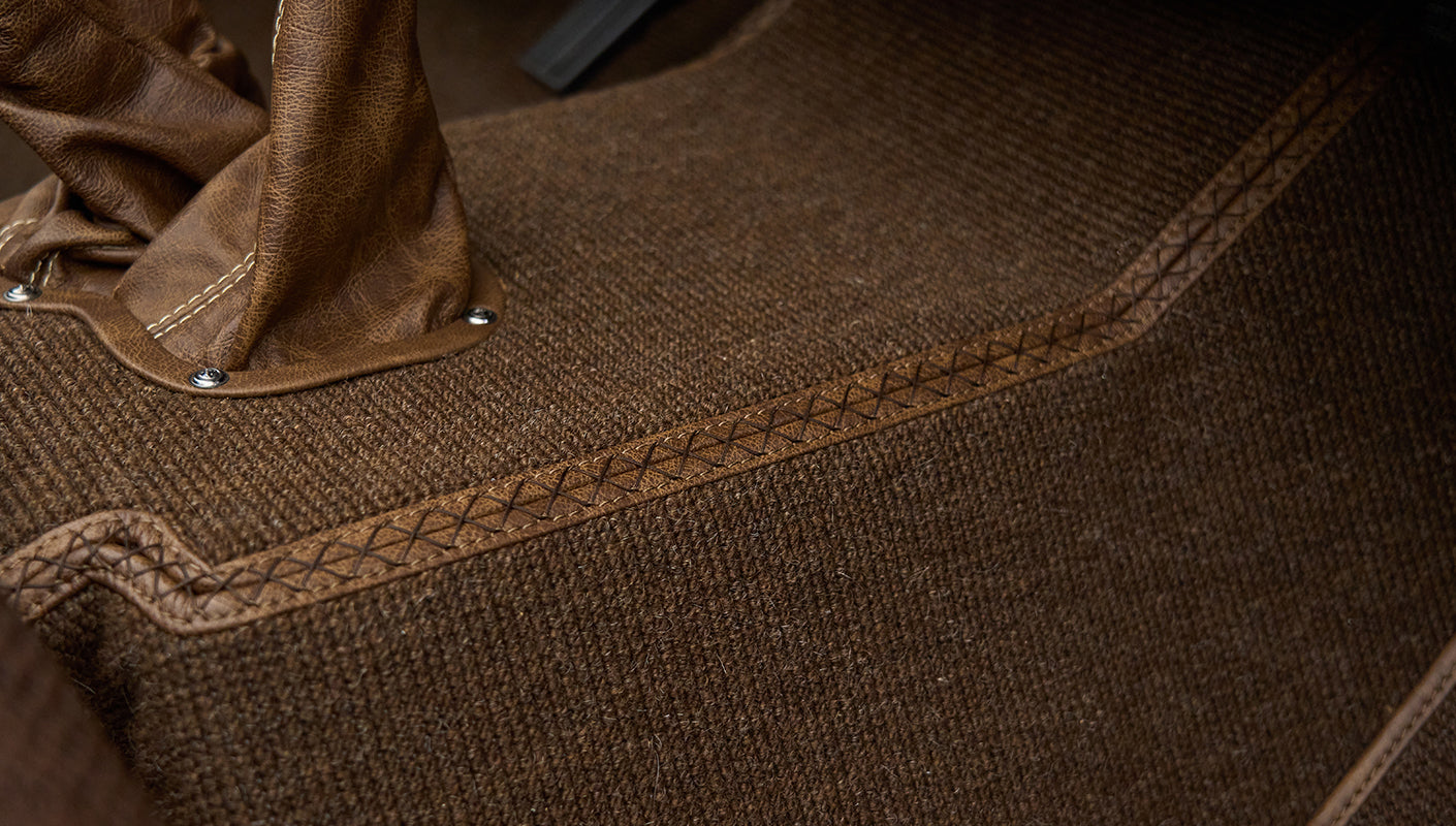 Detailed stitching on brown carpet floor with leather shift boot edge in Classic Ford Bronco interior