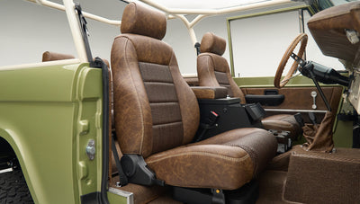 Interior side view of open door with vintage brown leather driver and passenger seats in Classic Ford Bronco