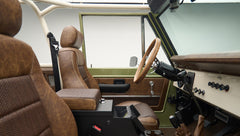Side view of front cabin with steering wheel, dashboard, and brown leather seats in Classic Ford Bronco Lime Gold