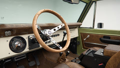 Steering wheel and dashboard of Classic Ford Bronco with gauges and gear shift visible