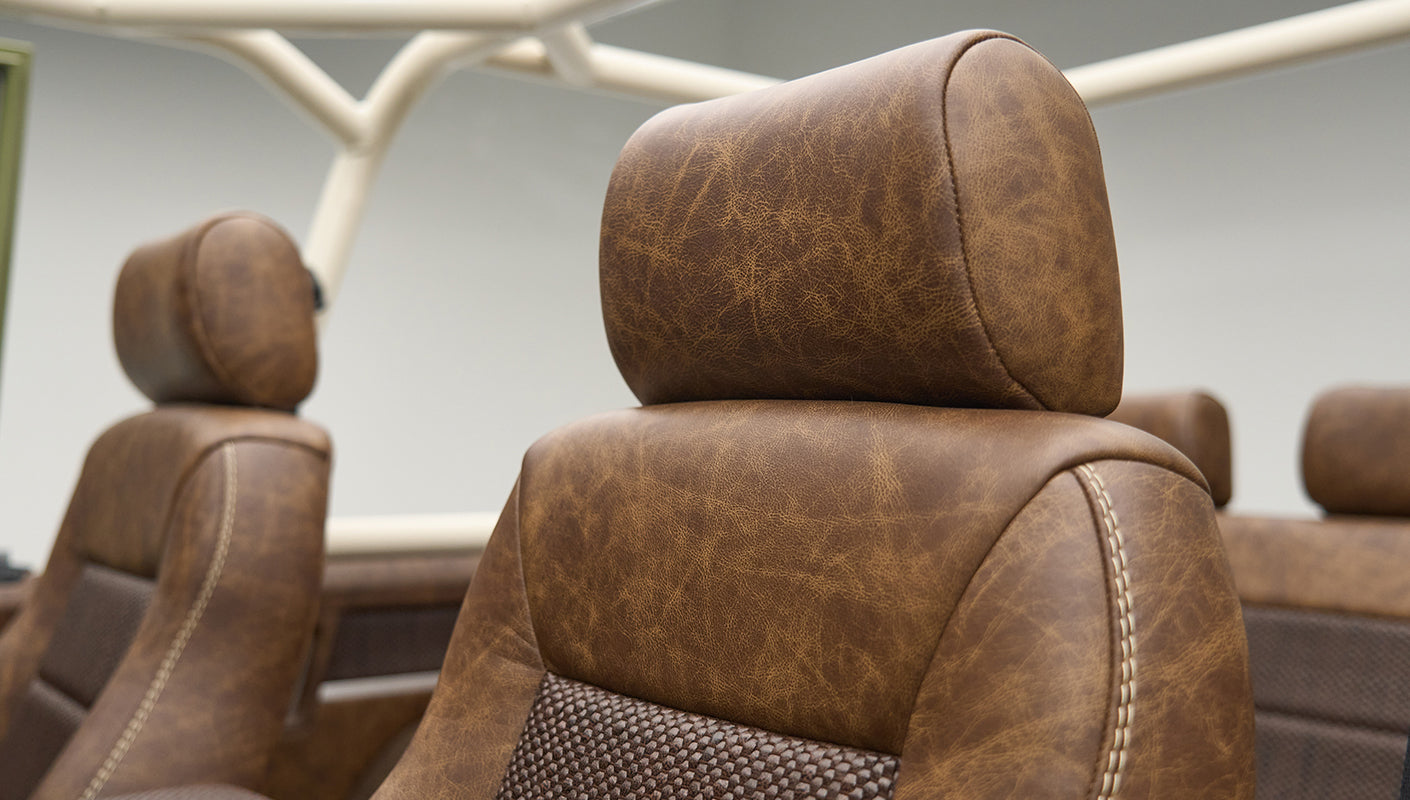Brown leather headrest and seat backs with visible roll cage in Classic Ford Bronco interior