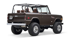 Classic Ford Bronco in matte brown with open roof and brown leather seats, rear angled view