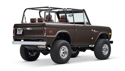 Classic Ford Bronco in matte brown with open roof and brown leather seats, rear angled view