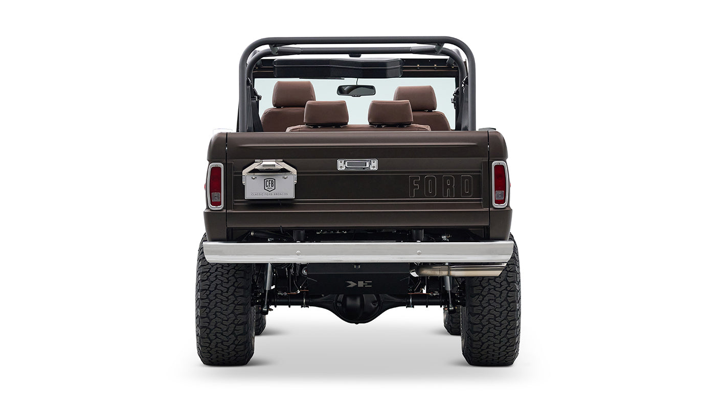 Rear view of matte brown Classic Ford Bronco with chrome bumper and visible suspension