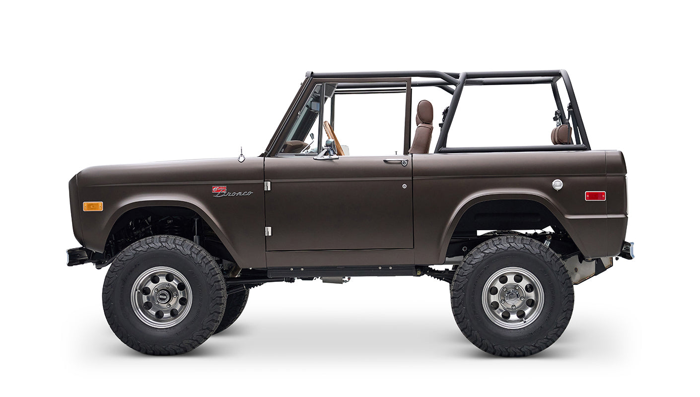 Side profile of matte brown Classic Ford Bronco with open roof and large off-road tires
