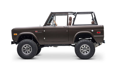 Side profile of matte brown Classic Ford Bronco with open roof and large off-road tires