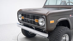 Close-up of classic Ford Bronco front grille, headlights, orange side marker, and steel bumper