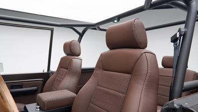Driver and passenger seats inside Classic Ford Bronco, matte brown leather and fabric upholstery