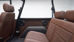 Back seat area showing side panels with speakers and seat belts inside matte brown Classic Ford Bronco
