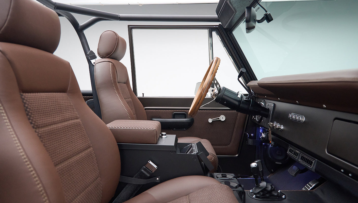 Driver side interior of Classic Ford Bronco showing brown seats and dashboard