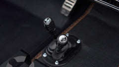 Close-up of gear levers on black floor mat with brown stitching inside Classic Ford Bronco interior