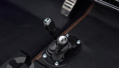 Close-up of gear levers on black floor mat with brown stitching inside Classic Ford Bronco interior