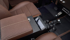 Center console with brown textured armrest and touchscreen control panel inside Classic Ford Bronco