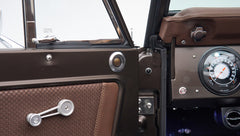 Close-up of Classic Ford Bronco's brown door panel with speaker and window crank
