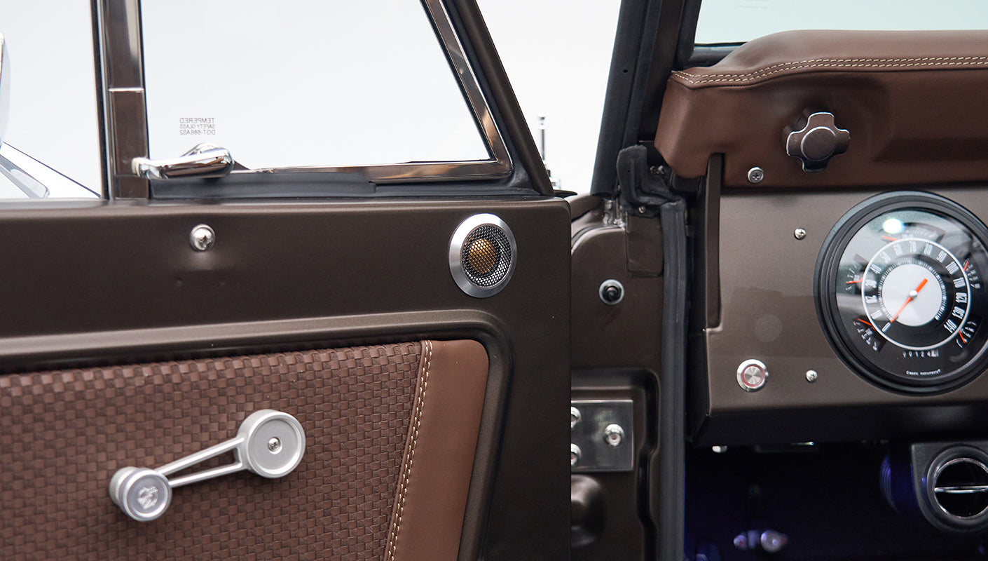 Close-up of Classic Ford Bronco's brown door panel with speaker and window crank