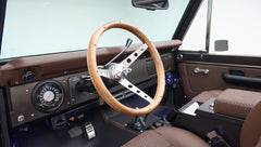 Classic Ford Bronco interior showing wood steering wheel and dashboard with gauges