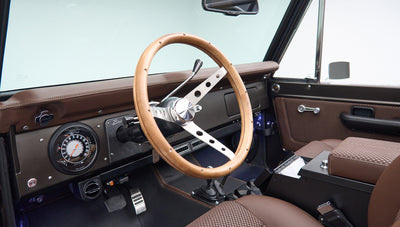 Classic Ford Bronco interior showing wood steering wheel and dashboard with gauges
