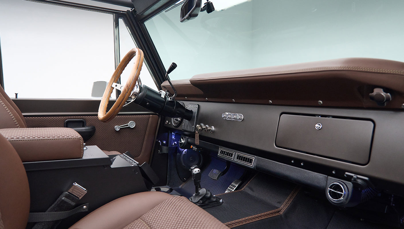 Classic Ford Bronco cabin view from driver side showing dashboard, steering wheel, and seats
